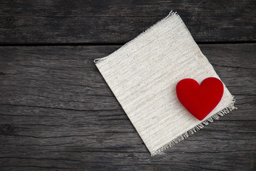 Vintage valentine concept, red heart over canvas fabric with space on dark wood texture background