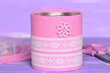 Felt and ribbon recycled tin can. Recycling tin cans into holder to contain pens, pencils, markers and other office supplies. Thrifty, quick and easy recycled home crafts concept. Closeup
