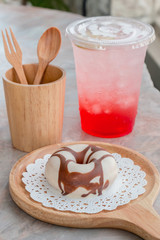 Glazed donut on wooden tray with soft drink
