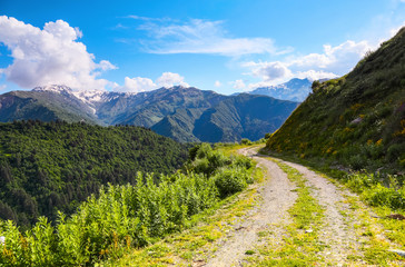 Fototapeta na wymiar A wide road with a cliff leads down to the high Caucasus mountains.