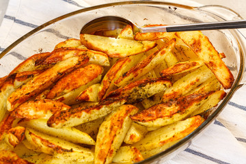 Homemade baked potatoes with spices in a glass form.