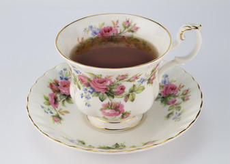 Full antique teacup and saucer with rose and gold decoration isolated on white