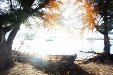 Old fishing boat anchored Aground on the beach Behind is a sea view and a group of white fishing boats on the sea.