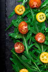 Obraz na płótnie Canvas Arugula salad with kumquat and tomato cherry on slate plate. Top view. Healthy food. Diet.