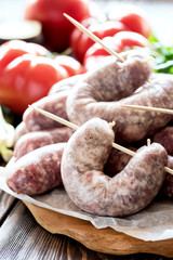 Close up raw sausages lying on wooden board Fresh vegetables and greens