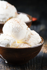 Vanilla ice cream balls, brown bowls, dark background, selective focus