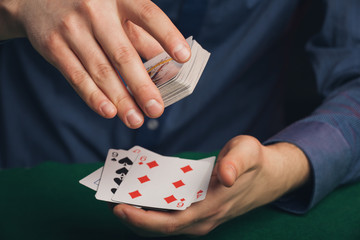 Poker game in men`s hands on green table