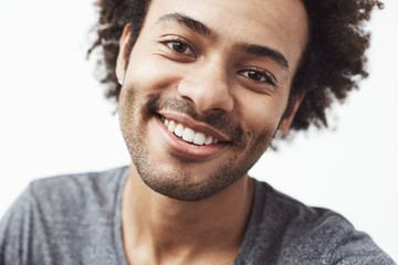 Obraz premium Close up portrait of handsome cheerful african man smiling looking at camera. White background.