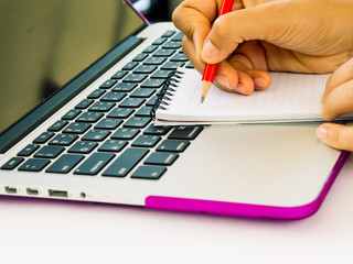 office accessories hand is writing note book on laptop