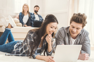 Fototapeta premium couple laying on carpet and using laptop