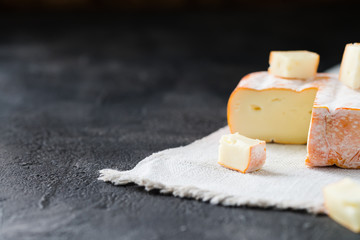 French soft cheese from Brittany region sliced on cloth on dark rustic background