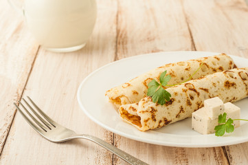 Food photography. Thin pancakes with filling and slices of cheese with herbs