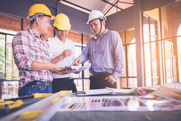 customer and constructor foreman worker with helmet and vest looking blueprints in new house building in real state business and housing industry concept. data in touch pad`