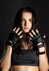 beautiful sexy female boxer or mma fighter wearing black gloves on a dark background