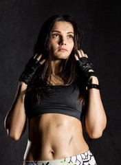 Fototapeta na wymiar strong sexy female boxer or mma fighter wearing black gloves on a dark background