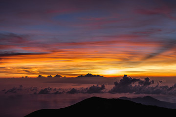 View of Rinjani peak from top of Agung volcano in Bali at sunrise summit. Sunrays and colorful sky, panoramic landscape, Agung trekking