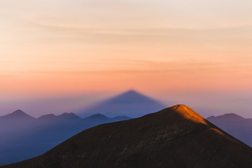 Crater rim of mount Agung in Bali at sunrise summit. Above the clouds, colorful landscape. First rays of rising sun in orange color. Top of Agung Volcano