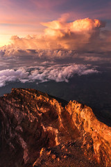 Crater rim of mount Agung in Bali at sunrise summit. Above the clouds, colorful landscape. First rays of rising sun in orange color. Top of Agung Volcano