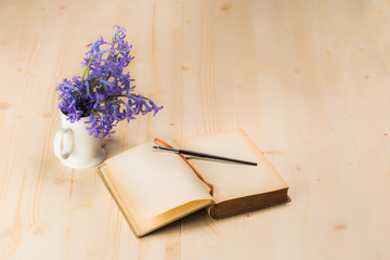 Fototapeta premium lily flowers with open aged notebook and brush on wooden table