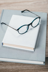 Two books and eyeglasses on table