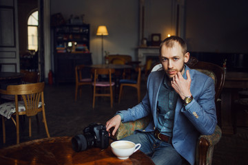 Young man sits and enjoys coffee in the morning. Portrait in the interior