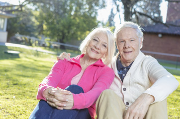 Elderly couple enjoying summer sunset relaxing on garden grass