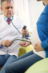 Doctor measures the pressure of a pregnant woman