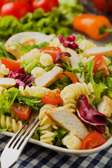 Noodle salad with green lettuce, tomatoes and roasted chicken.