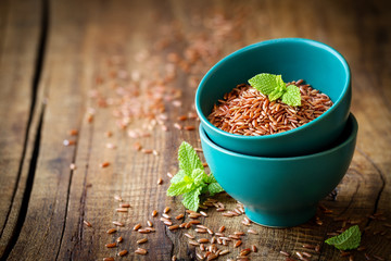 Red rice an a small ceramic bowl against dark rustic wooden background