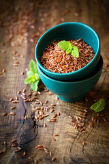 Red rice an a small ceramic bowl against dark rustic wooden background