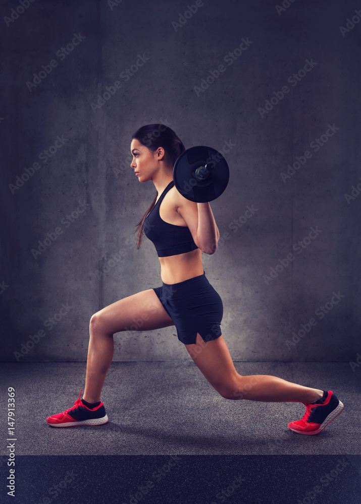 Canvas Prints young woman flexing muscles with barbell in gym