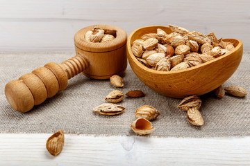 Almonds in their skins and peele in brown bowl on wooden background. Healthy food