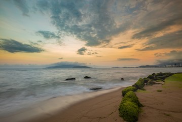 A view of Nha Trang bay just after sunset with moss covered rocks in the foreground.