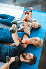Happy family exercising with dumbbells at fitness studio