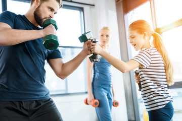 Happy family exercising with dumbbells at fitness studio
