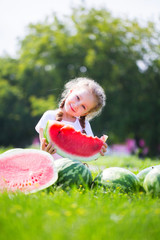 Little girl with big slice watermelon in summer time in park.