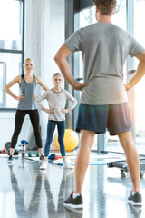 Fototapeta premium Young woman and cute girl exercising with coach at fitness studio