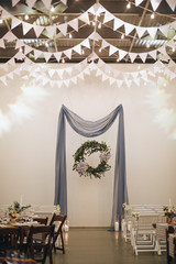 A wedding bouquet of bride stands on the table in the wedding banquet area, beside it there are candles and glass boxes with succulents