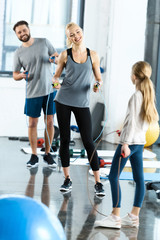 Young parents and daughter with skipping ropes at health club