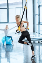 Blonde fitness woman training with fitness straps