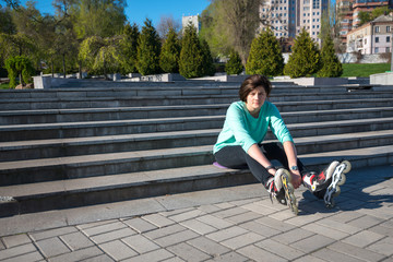 Tired girl sits on the steps in the park, stretching out her legs