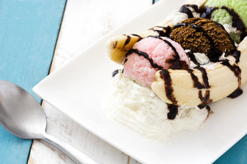 Banana split ice cream dessert with chocolate syrup on white and blue wooden table
