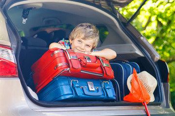 Little kid boy sitting in car trunk just before leaving for vaca