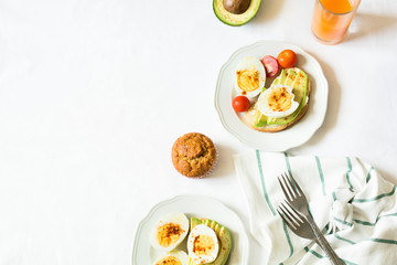 Healthy breakfast: toasts with avocado slices, tomato, paprika and eggs on white tableware. Selective focus