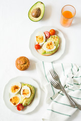 Healthy breakfast: toasts with avocado slices, tomato, paprika and eggs on white tableware. Selective focus