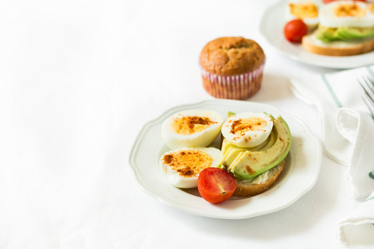 Healthy breakfast: toasts with avocado slices, tomato, paprika and eggs on white tableware. Selective focus