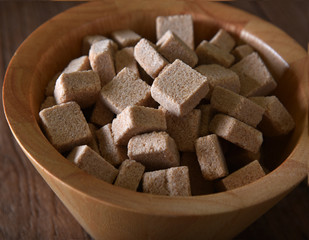 Fototapeta na wymiar Brown sugar cubes in bowl. Top view