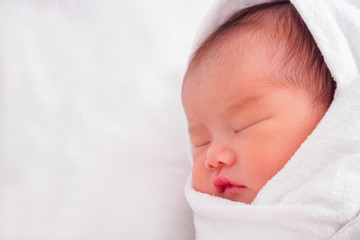 Cute newborn asian baby girl sleeping on white fabric