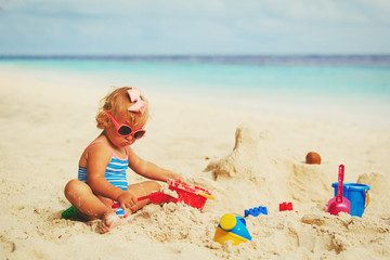 Fototapeta na wymiar cute little girl playing with sand on beach