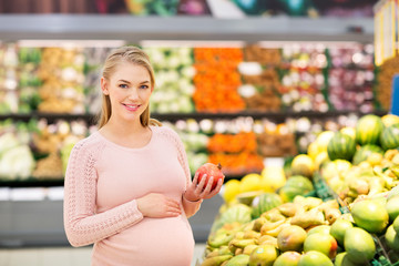 happy pregnant woman with pomegranate at grocery